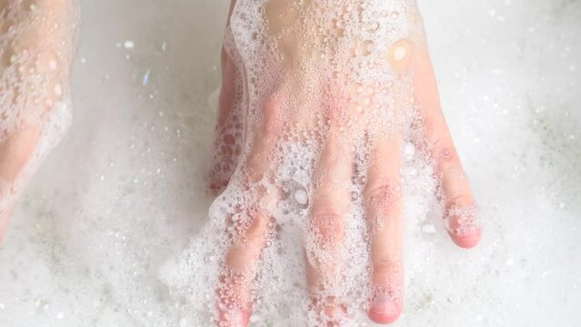 Female hands are washing with soap bubbles. Foammy massage. Wellness concept