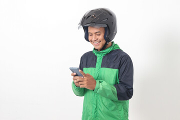 Portrait of Asian online taxi driver wearing green jacket and helmet holding mobile phone with smiling expression face. Isolated image on white background