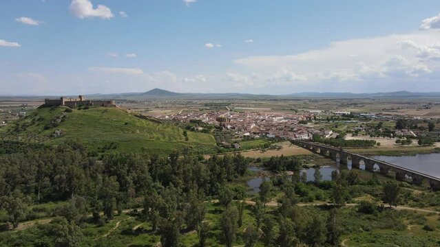 Aerial overview of Medellin town, Badajoz Spain.  Castle's ancient walls hug the town, while the historic bridge spans the river, connecting past and present in a timeless embrace.