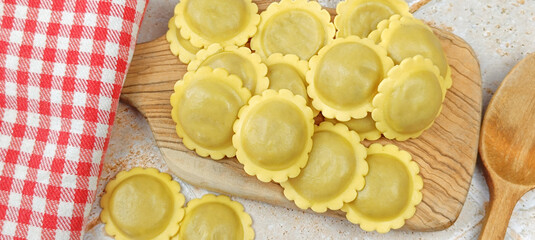 tas de raviolis crus, en gros plan, sur une planche à découper