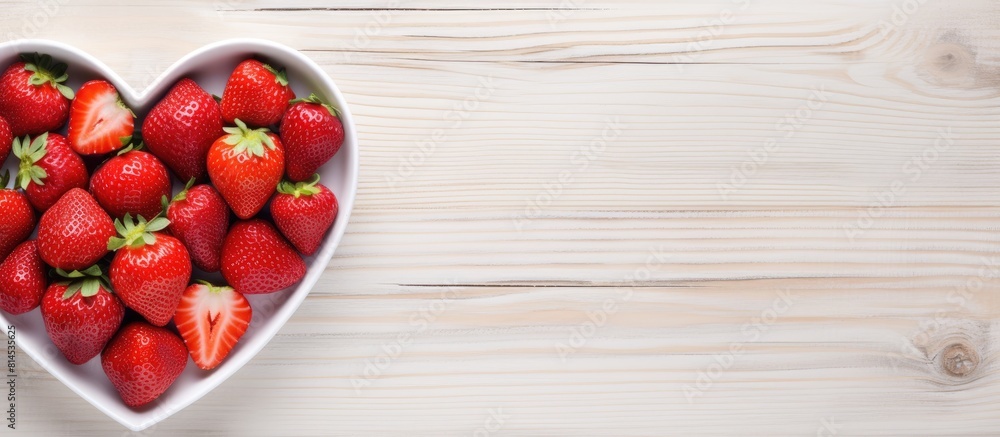 Poster a top view of a plate filled with fresh strawberries arranged in the shape of a heart placed on a wh