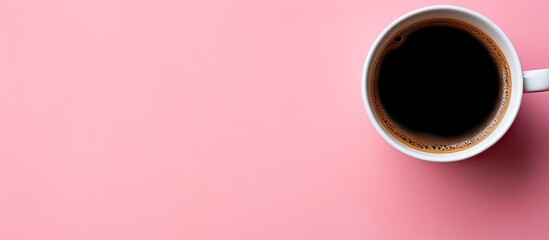 A black coffee cup is seen from above on a pink background with ample space for additional imagery or text