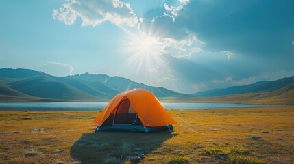 An orange tent pitched up in a green field with majestic mountains in the background under a clear blue sky - Powered by Adobe