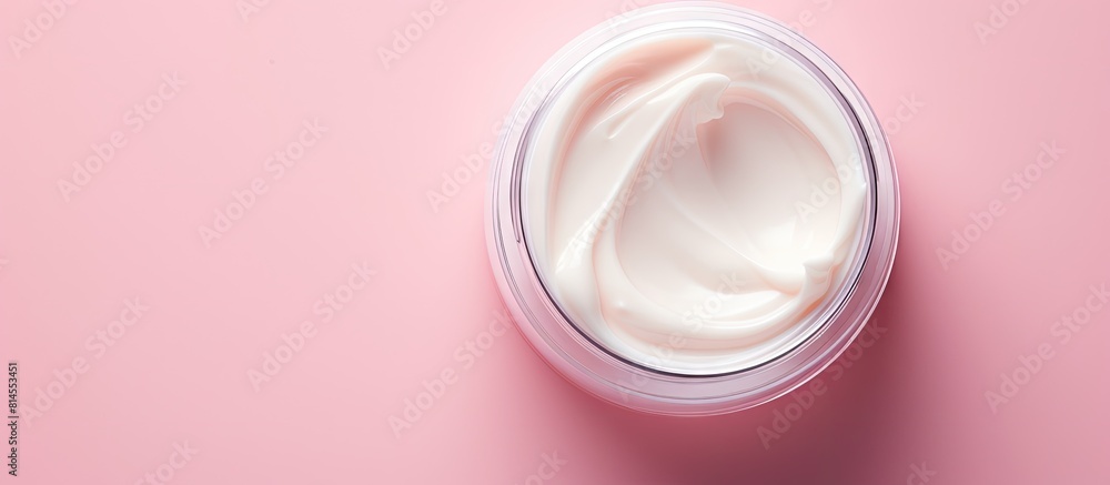 Poster Top view of a moisturizer with a half opened lid placed on a light pink background in a flat lay style with copy space image
