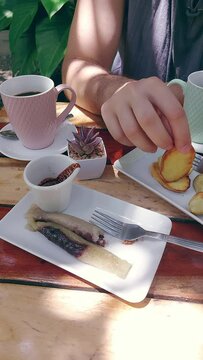 Vertical. Eating fried kamote slices or sweet potato served along with coffee and suman budbud or steamed glutinous rice cake that are traditional local Filipino merienda food