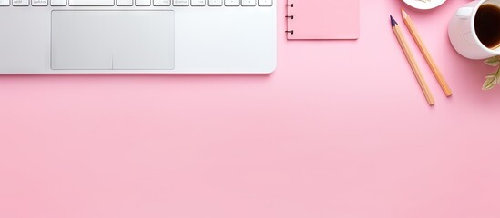 Flat lay copy space image of stationery and keyboard on a pink table top showcasing the concept of online education