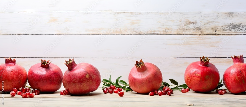 Poster a copy space image of pomegranates resting on a white wood table