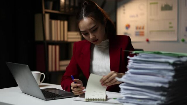 Serious business woman is stressed and bored with too much paperwork to miss the deadline. She is working tiring overtime. Overworked woman is stressed over unfinished paperwork.
