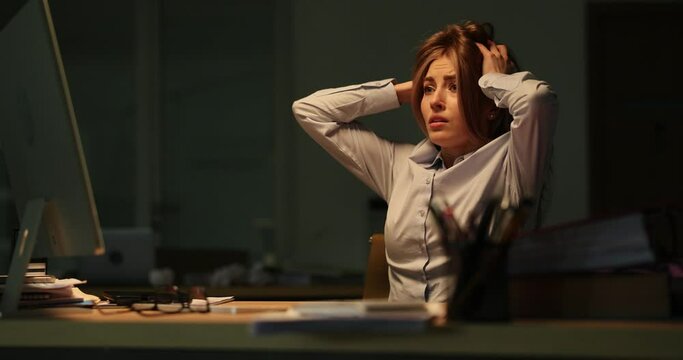 Tired businesswoman grabbing head in front of computer during thunderstorm in office 4k movie. Chaos and problems at work concept