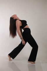 Portrait of a beautiful fashion model in the studio on a light background, wearing a black short...