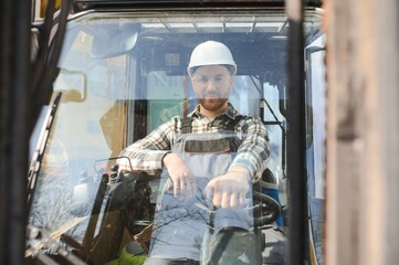 A man on a forklift works in a large warehouse, unloads bags of raw materials