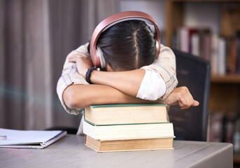 Headphones, books and girl with sleeping in library for studying, burnout and knowledge for exam. University, student and tired with rest on table for scholarship, education or deadline of assignment