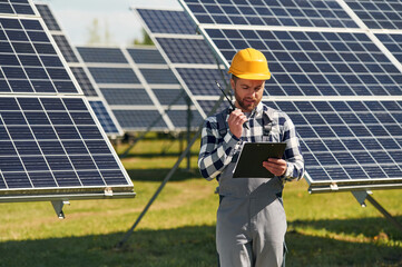Communication by using walkie talkie. Engineer with photovoltaic solar panels outdoors at daytime
