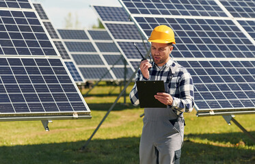 Talking by radio. Engineer with photovoltaic solar panels outdoors at daytime