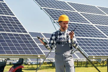 Talking by radio. Engineer with photovoltaic solar panels outdoors at daytime
