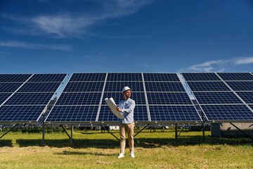 Distant view. Engineer with photovoltaic solar panels outdoors at daytime