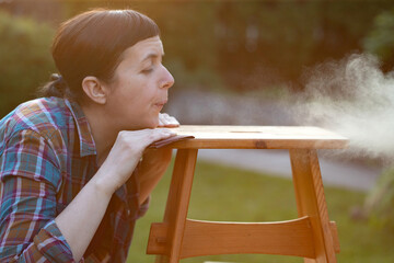 Woman sanding a wooden furniture outdoors, an eco-friendly re-use business.