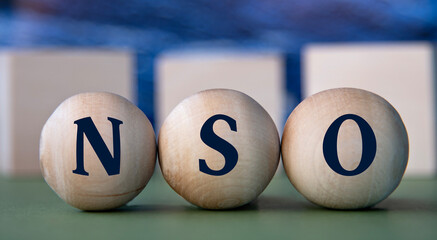 NSO - acronym on wooden balls on the background of wooden large cubes