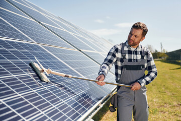 Process of cleaning the surface. Engineer with photovoltaic solar panels outdoors at daytime