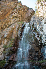 .waterfall among the rocks. The mountain waterfall is surrounded by large cliffs and steep slopes.