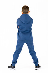 Cheerful boy in blue tracksuit on white background. Pretty boy,. Baby model. A little boy poses on a white background.Standing with his back