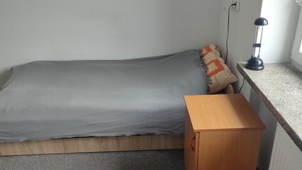 Bed and room in a student dormitory or inexpensive hostel. Minimalistic room interior