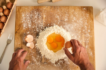 Overhead Shot Of Man At Home In Kitchen Mixing Eggs With Flour Making Dough On Worktop Or Counter