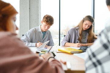 Fototapeta premium students sit at shared desk making notes studying together at university