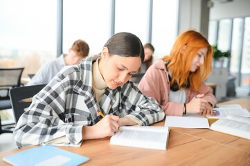 Fototapeta premium students sit at shared desk making notes studying together at university