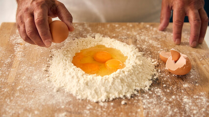 Overhead Shot Of Man At Home In Kitchen Mixing Eggs With Flour Making Dough On Worktop Or Counter