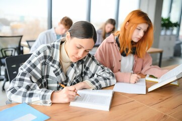 Obraz premium students sit at shared desk making notes studying together at university
