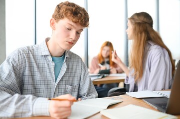 Obraz premium Testing. Closeup of young students sitting in a row and having test in their test-books