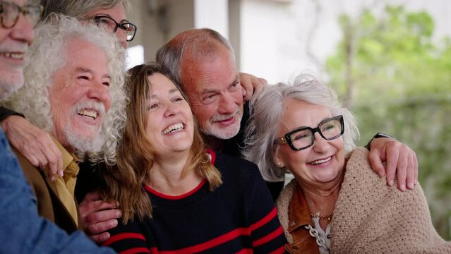 Group joyful seniors Caucasian people posing for picture laughing together sitting at cafeteria. Older cheerful friends with gray hair embracing. Lifestyle happy matures having fun in nursing home