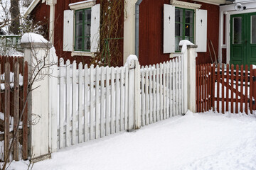 Garden rustic design. Authentic old retro vintage style wooden white gate entrance to the garden or courtyard. Countryside authentic cozy little house in rural area. Winter snowy view.