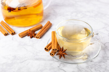 Fragrant hot tea with cinnamon stick and anise on a textured wooden background. A cup of hot tea...