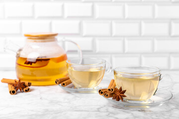 Fragrant hot tea with cinnamon stick and anise on a textured wooden background. A cup of hot tea...