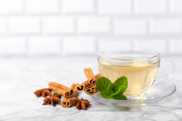 Fragrant hot tea with cinnamon stick and anise on a textured wooden background. A cup of hot tea...