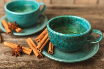 Fragrant hot tea with cinnamon stick and anise on a textured wooden background. A cup of hot tea with honey, lemon, mint and apples. Spicy tea with spices. Immunity tea. Health concept.Copy space.