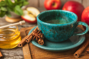 Fragrant hot tea with cinnamon stick and anise on a textured wooden background. A cup of hot tea...