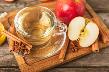 Fragrant hot tea with cinnamon stick and anise on a textured wooden background. A cup of hot tea with honey, lemon, mint and apples. Spicy tea with spices. Immunity tea. Health concept.Copy space.