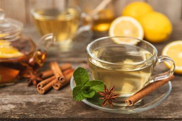 Fragrant hot tea with cinnamon stick and anise on a textured wooden background. A cup of hot tea with honey, lemon, mint and apples. Spicy tea with spices. Immunity tea. Health concept.Copy space.