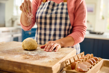 Close Up Of Woman At Home In Kitchen Sprinkling Flour On Dough On Worktop Or Counter
