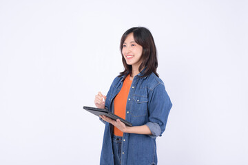 Asian woman wearing orange shirt and denim jean jacket is holding a tablet and a stylus against a white background.