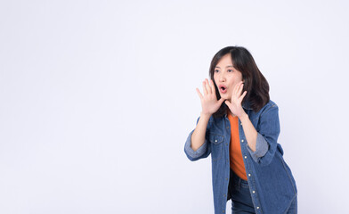 Asian woman wearing orange t shirt and denim jean is posing with a shouting gesture against a white background.
