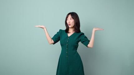 Happy Asian woman presenting or showing open hand palm with copy space for product isolated over green background