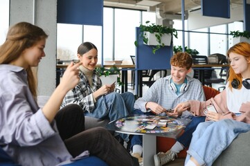 Group of creative friends sitting at wooden table. People having fun while playing board game