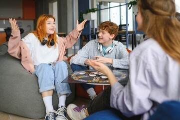 Group of creative friends sitting at wooden table. People having fun while playing board game