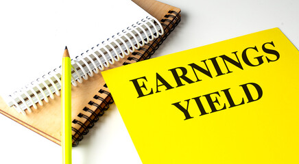 EARNINGS YIELD text on yellow paper with notebooks