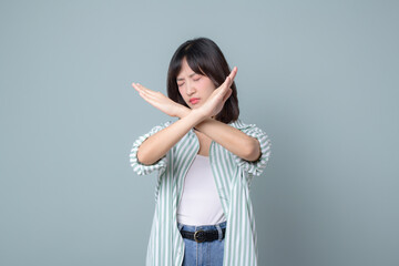 serious asian woman shows cross hands gesture, stop sign, taboo, disapproves bad action, stands in...
