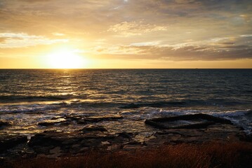 Obraz premium Scenic view of a tranquil beach against the sea at sunset